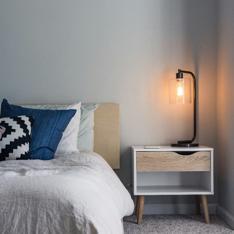 Černá stolní lampa se skleněným stínidlem na nočním stolku v ložnici