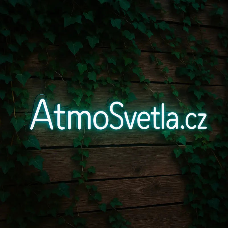 Bílý LED neonový nápis AtmoSvetla.cz na tmavé dřevěné stěně s břečťanem