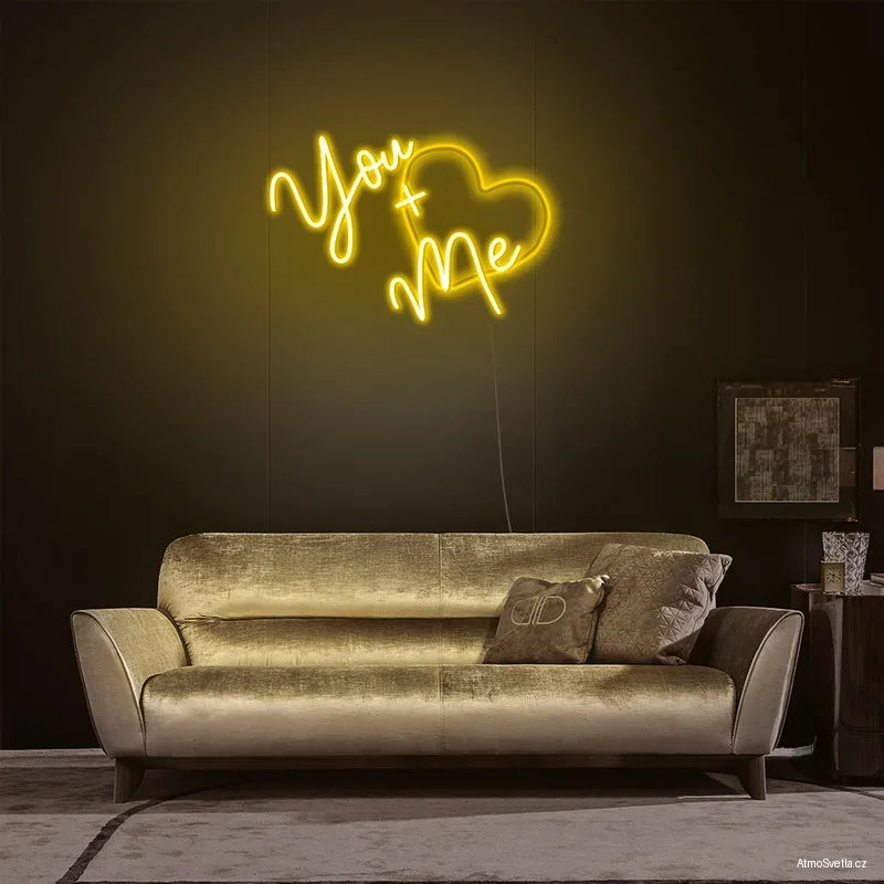 Žlutý LED neon You + Me nad sedačkou, designové interiérové osvětlení v minimalistickém stylu.
