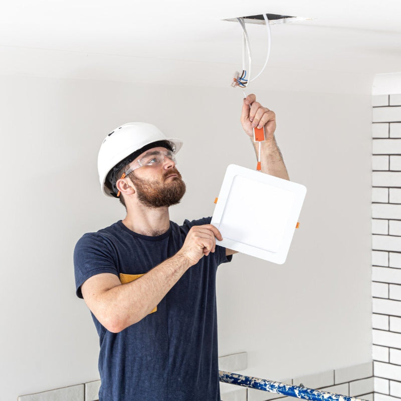 Elektrikář v helmě montuje čtvercové LED stropní svítidlo