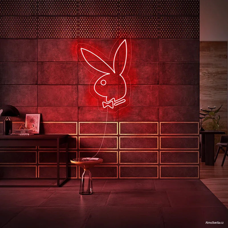 Červený neonový symbol Playboy zajíčka vytvářející intimní atmosféru v interiéru.