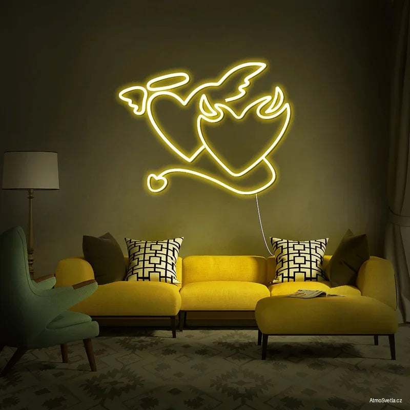 Žlutý LED neon anděl a ďábel – energické dekorativní osvětlení nad žlutou sedačkou.