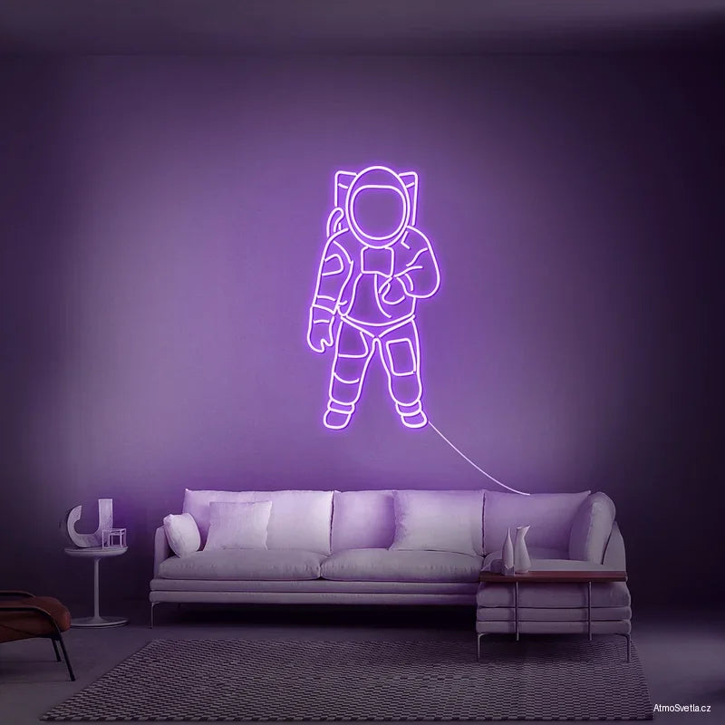 Fialový neonový nápis astronaut, futuristický LED prvek nad postel.