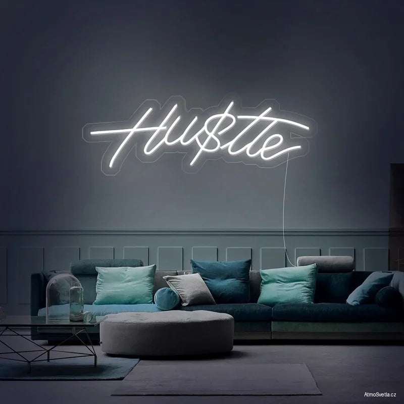 Bílý motivační neonový nápis Hustle na stěně v moderním obývacím pokoji.