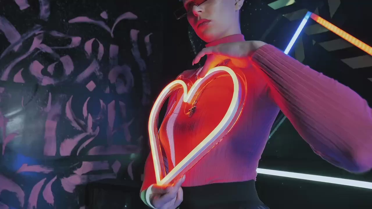 Vlastní LED neon srdce v růžové barvě – dívka v růžovém drží neon na míru a vede po něm prstem, kamera zoomuje. Návrh zdarma do 5 hodin, neon u vás do 14 dnů s dopravou zdarma po ČR.