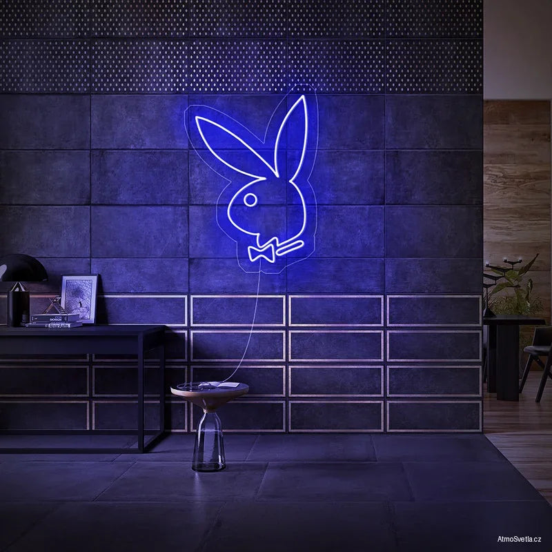 Tmavě modrý LED neon Playboy zajíček zářící v luxusním tmavém interiéru.
