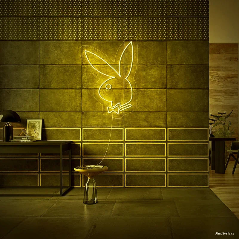Žlutý LED neonový nápis Playboy na industriální stěně s kovovými prvky.