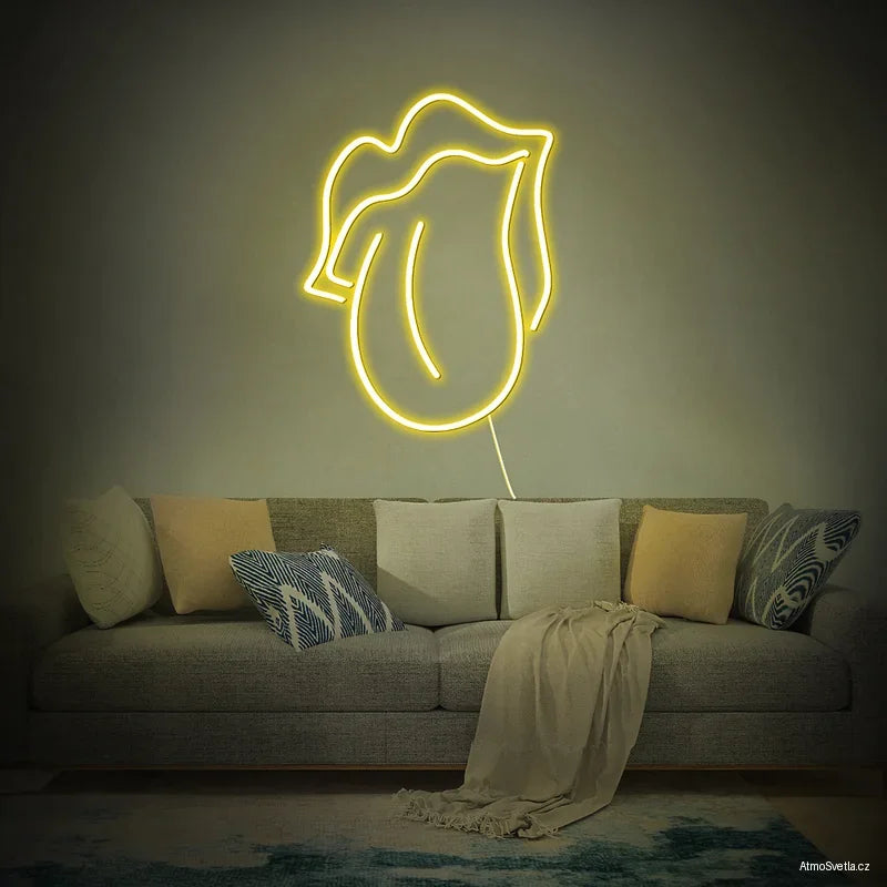 Žlutý neonový nápis vyplazený jazyk, zářivý dekorativní prvek na stěnu.